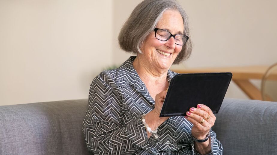 Smiling senior woman relaxing at home with a tablet