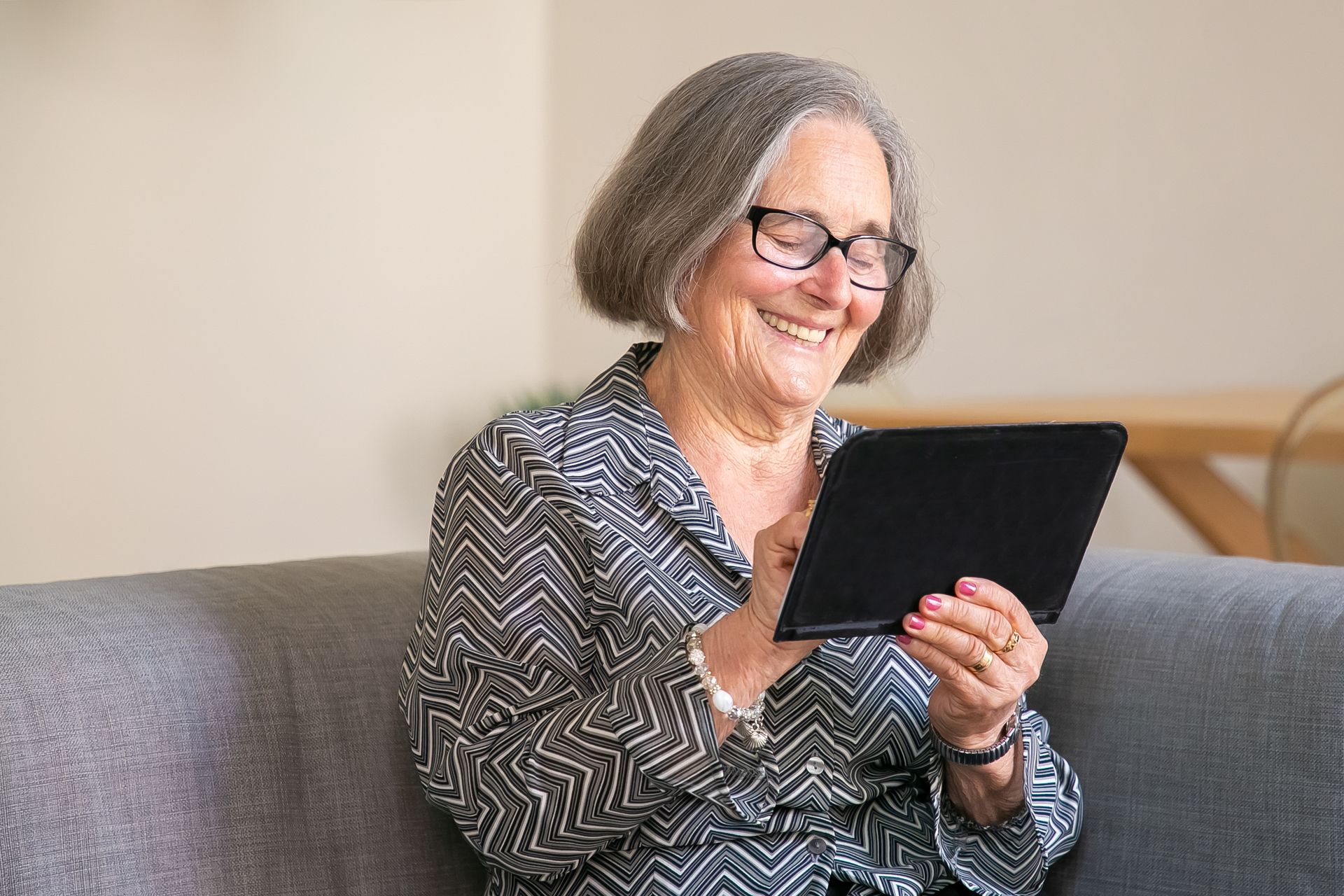 Smiling senior woman relaxing at home with a tablet